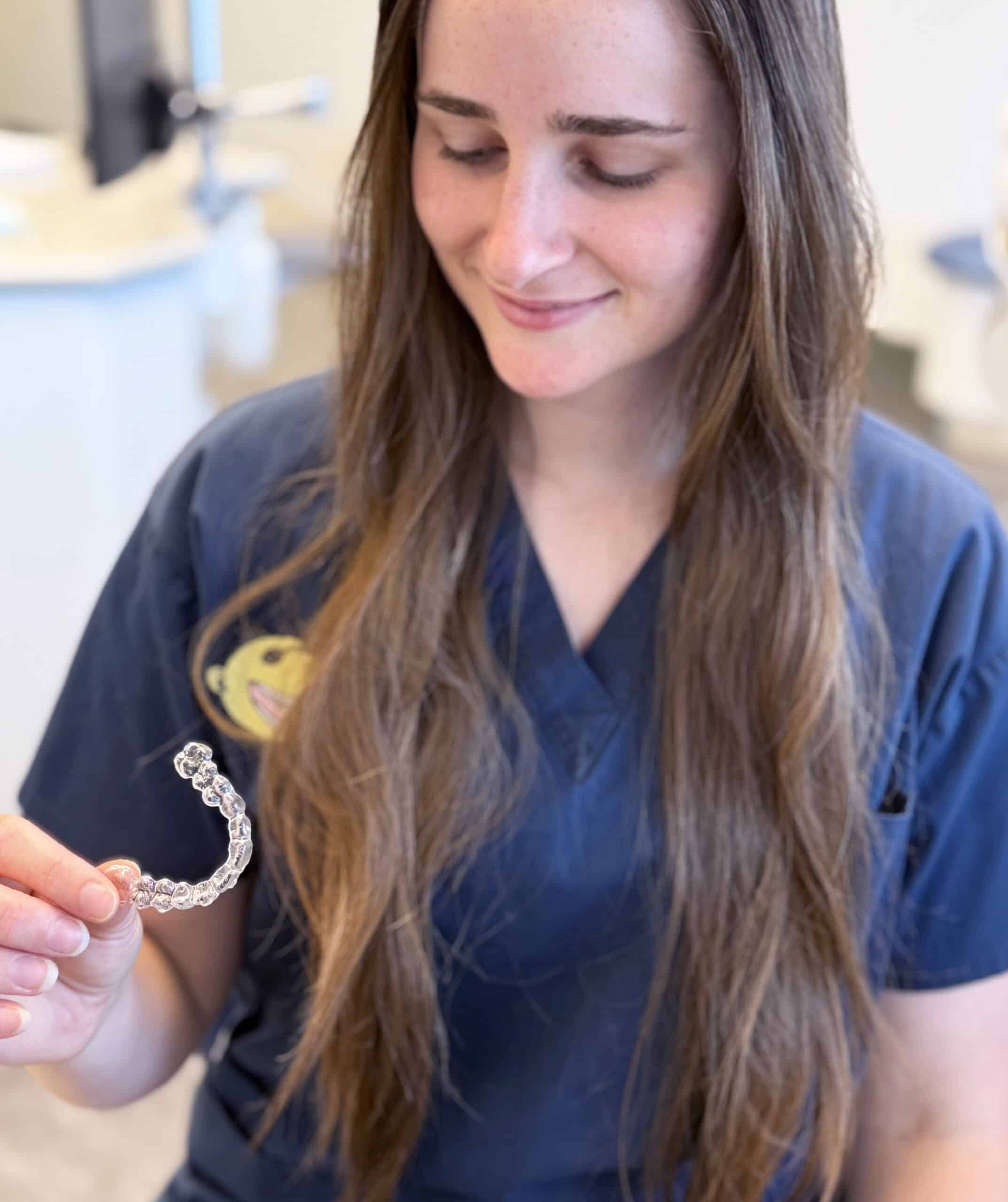 Invisalign aligner held by Fine Orthodontist Sydney staff member.