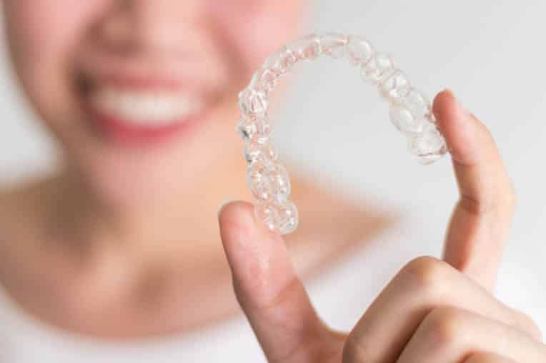 Invisalign clear aligners held in woman's hand.