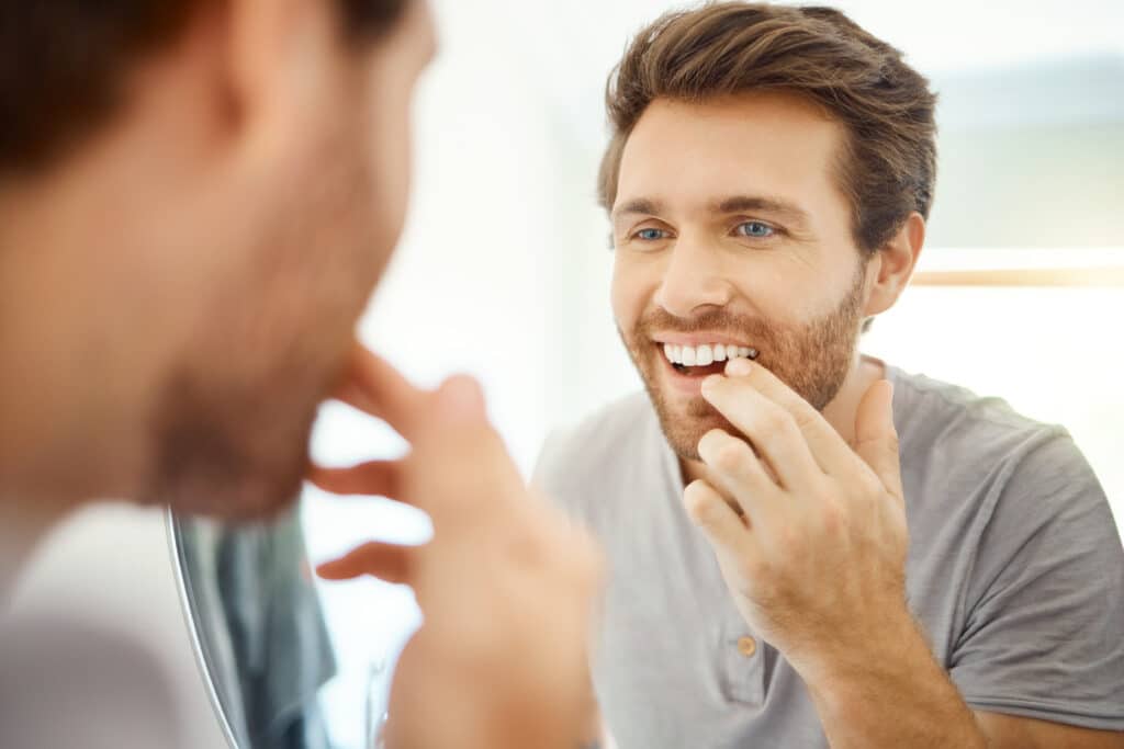 Man looks into mirror wondering if Invisalign can fix his overbite.