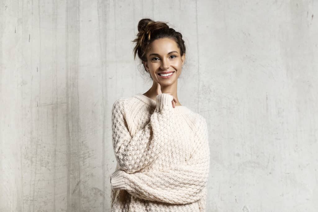 Woman thinking, deciding between Invisalign versus veneers.