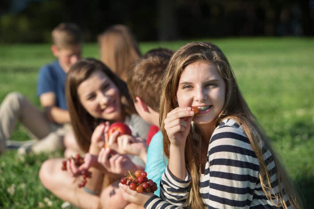 Eating with braces - group outdoors eating grapes during braces treatment.