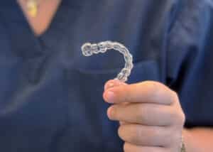 Invisalign aligner held by Fine Orthodontist Sydney staff.