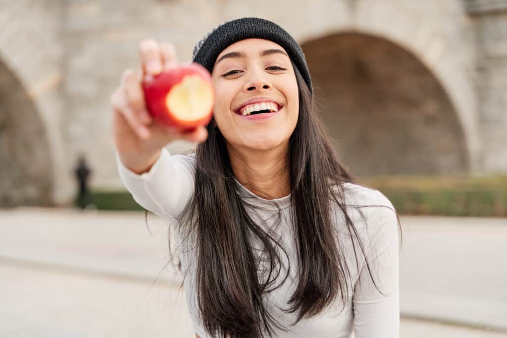 Young woman eating an apple during Invisalign treatment.