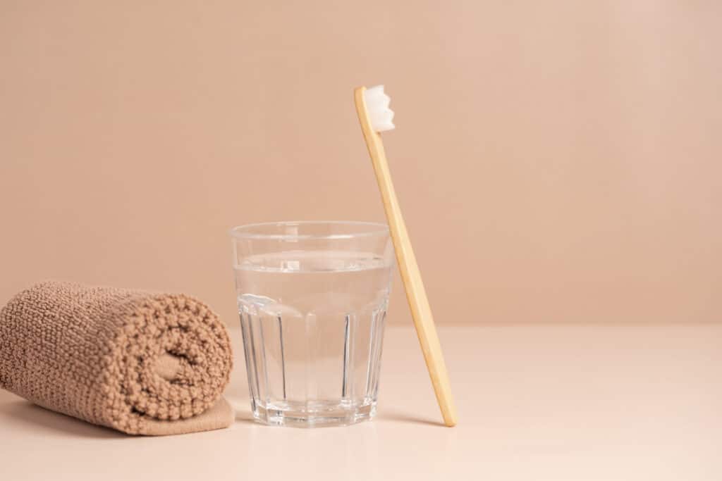 Invisalign cleaning accessories - toothbrush, glass of water and a towel.