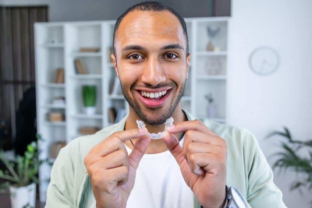 Man putting in invisible braces clear aligners for dental correction.