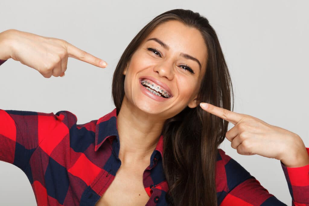 Smiling young woman wearing metal braces.
