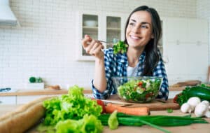 Girl smiling eating salad wondering what can you eat with Invisalign?