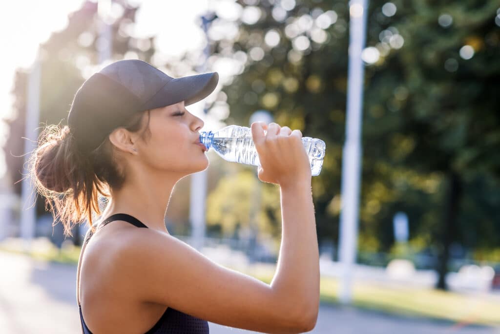 Woman outside exercising, drinking water during Invisalign treatment.