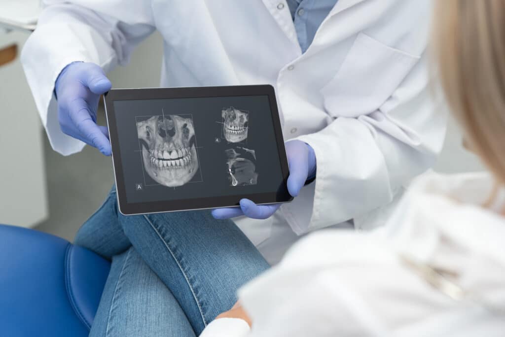 Orthodontist in clinic showing patient 3D x-rays to assist with planning corrective jaw surgery.