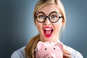 Young woman wondering if medicare covers braces, holding a piggybank.