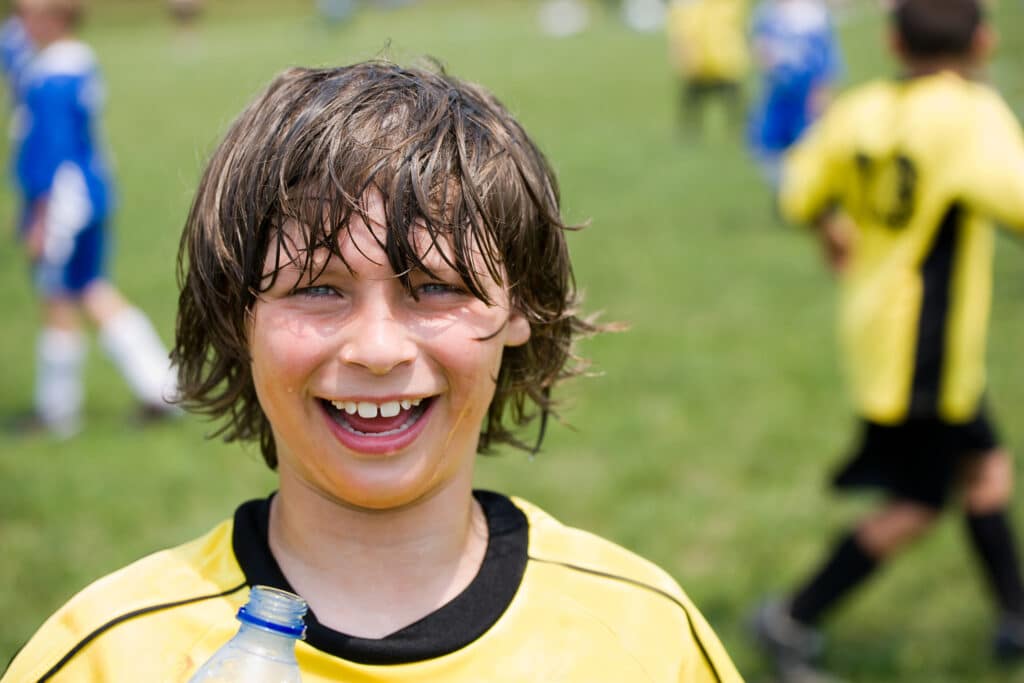Orthodontic patient (young boy) outside playing sport.